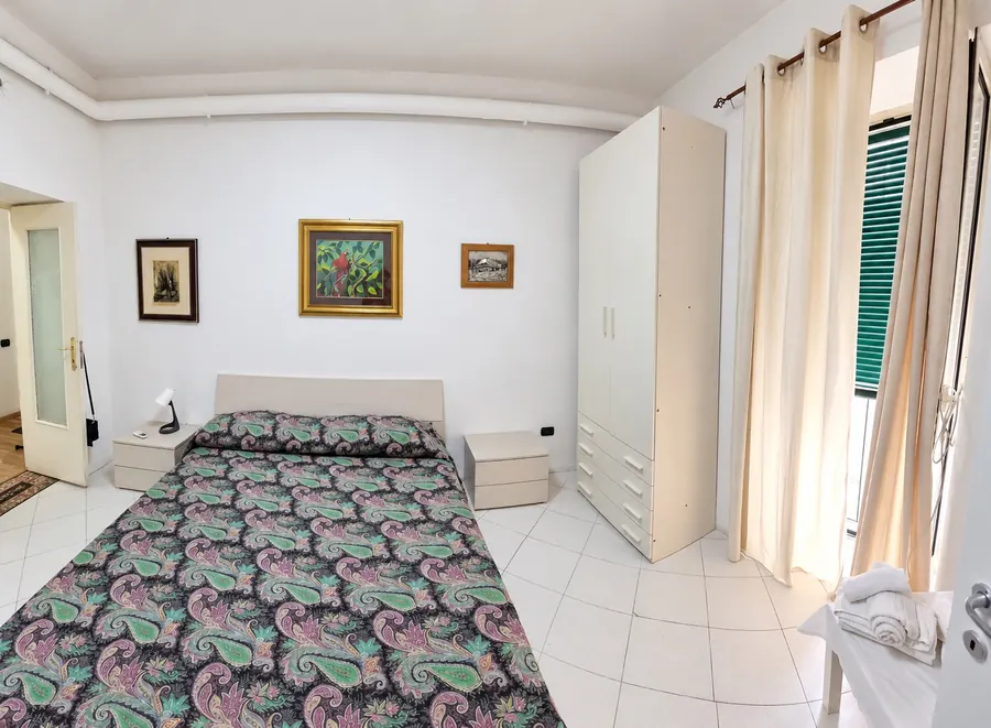 Doppelzimmer mit gemusterter Tagesdecke und weißem Kleiderschrank
