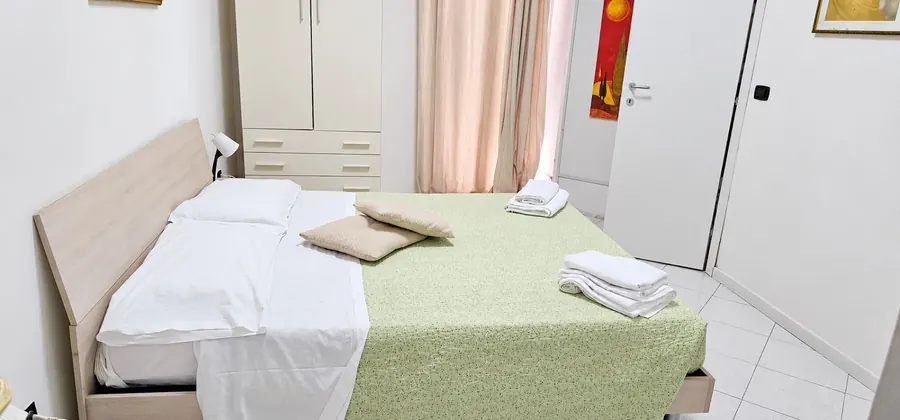 Helles Zimmer mit weiß-grünem Bett und Marmorboden